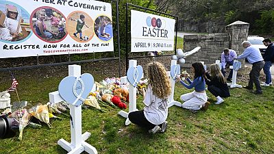 Girls write messages on crosses at an entry to Covenant School, Tuesday, March 28, 2023, in Nashville, Tennessee, after Monday's school shooting
