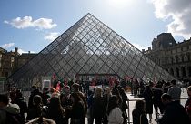 Visitors wait as workers of the culture industry demonstrate outside the Louvre museum.