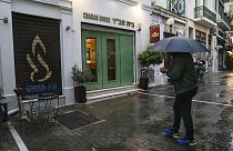 رجل يقف أمام مطعم يهودي يعتقد المسؤولون اليونانيون أنه كان أحد أهداف هجوم إرهابي مخطط له، في وسط أثينا، 28 مارس، 2023