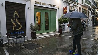 رجل يقف أمام مطعم يهودي يعتقد المسؤولون اليونانيون أنه كان أحد أهداف هجوم إرهابي مخطط له، في وسط أثينا، 28 مارس، 2023