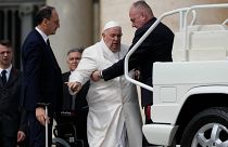 Pope Francis gets help from his security people.