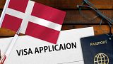 فرم در خواست ویزای دانمارک در کنار پرچم و پاسپورت این کشور