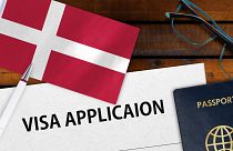 فرم در خواست ویزای دانمارک در کنار پرچم و پاسپورت این کشور