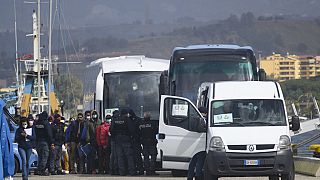 (File) People wait to board buses after they disembarked from the Diciotti Italian Coast Guard ship in Reggio Calabria, southern Italy, Wednesday, March 15, 2023.