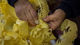 Angela Pastor decorates a palm to be used during Palm Sunday processions at a shop in Elche, eastern Spain, Tuesday, March 21, 2023