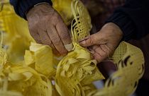 Angela Pastor decorates a palm to be used during Palm Sunday processions at a shop in Elche, eastern Spain, Tuesday, March 21, 2023