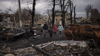 Семья проходит мимо уничтоженных российских танков. Буча, Украина. 6 апреля 2023.