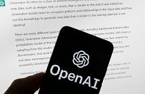 The OpenAI logo is seen on a mobile phone in front of a computer screen displaying output from ChatGPT, Tuesday, March 21, 2023, in Boston, USA.