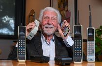 المهندس الأمريكي مارتن كوبر يحمل بيده اليمنى نسخة من أول هاتف محمول استعمله لإجراء أول اتصال قبل نصف قرن