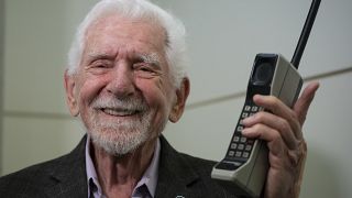 Marty Cooper posiert mit einem Motorola DynaTAC 8000x auf dem Mobile World Congress 2023 in Barcelona.