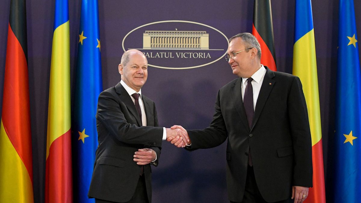 German Chancellor Olaf Scholz shakes hands with his Romanian counterpart Nicolae Ciuca at the Victoria Palace, the Romanian government headquarters.