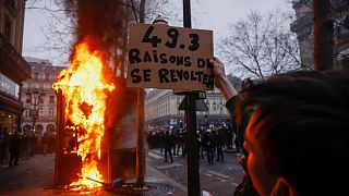 A protester holds a placard that reads, "49.3, reason to rebel", march at the end of a rally in Paris, 23 March 2023.