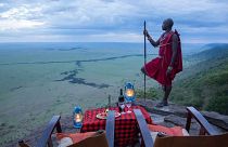 A man stands near a picnic table on a mountain, Kenya