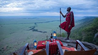 A man stands near a picnic table on a mountain, Kenya
