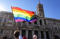 A demonstrator waves the rainbow flag in front of the Basilica of Saint Mary Major during the annual Pride march, in Rome, Saturday, June 26, 2021.
