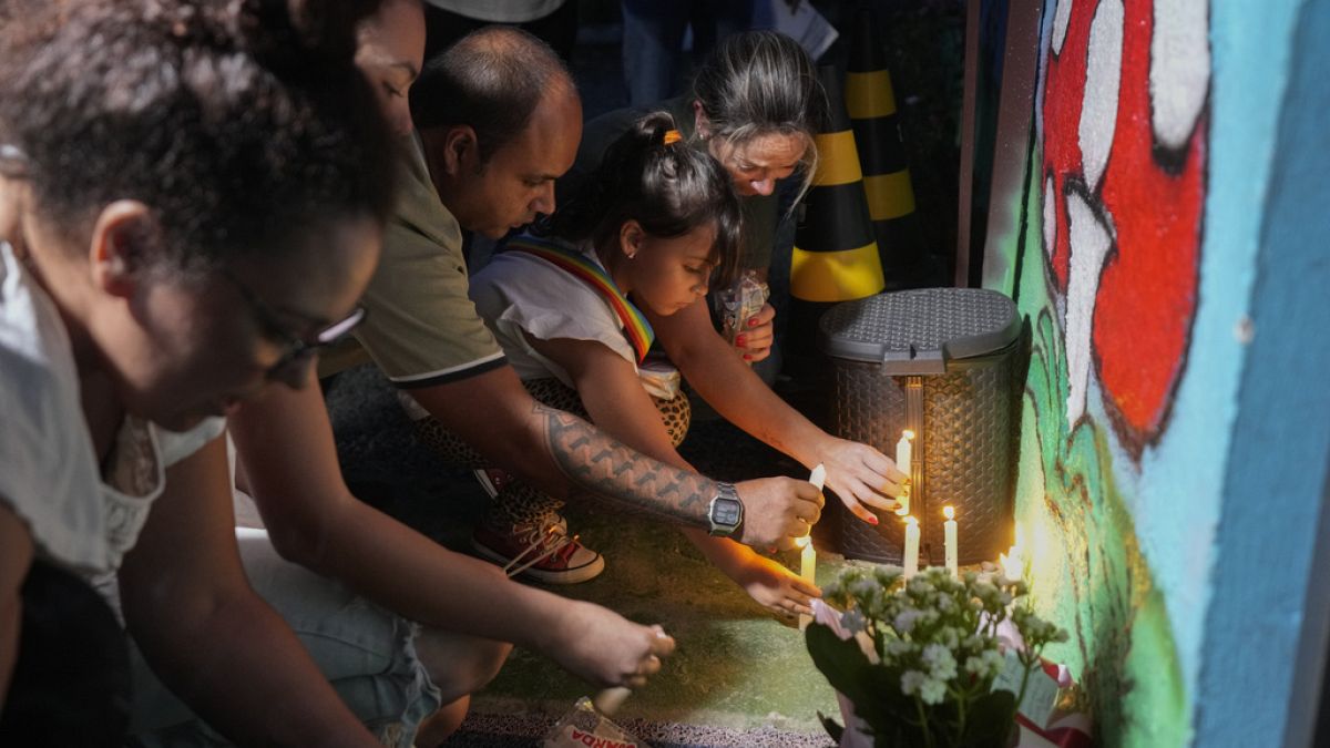 People place lit candles outside the "Cantinho do Bom Pastor" daycare center after a fatal attack on children in Blumenau, Brazil, Wednesday, April 5, 2023.
