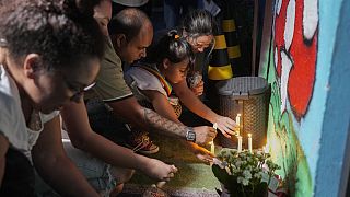 People place lit candles outside the "Cantinho do Bom Pastor" daycare center after a fatal attack on children in Blumenau, Brazil, Wednesday, April 5, 2023.