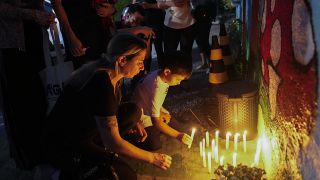 Varias personas colocan velas encendidas en el exterior de la guardería "Cantinho do Bom Pastor" tras un ataque mortal contra niños en Blumenau, Brasil, 5/4/2023