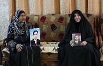 نضال علي [يمين] ونوال سويدان [يسار]، والدتان شيعية وسنيّة، تحملان صورة ابنيهما المفقودين
