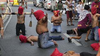Hooded Filipino flagellants pray along a street as part of Maundy Thursday rituals to atone for sins or fulfill vows for an answered prayer at Mandaluyong city, Philippines