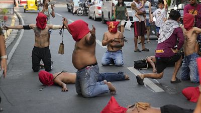 Hooded Filipino flagellants pray along a street as part of Maundy Thursday rituals to atone for sins or fulfill vows for an answered prayer at Mandaluyong city, Philippines