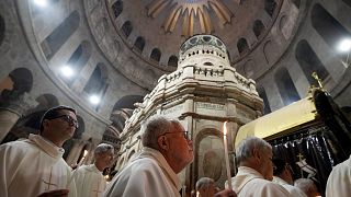 رجال دين كاثوليك يحملون الشموع خلال موكب الخميس المقدس في كنيسة القيامة