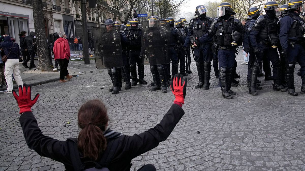 زنی در جریان تظاهرات پنجشنبه ۶ آوریل ۲۰۲۳ در پاریس، دستان خود را در مقابل افسران پلیس ضدشورش بالا می‌برد.