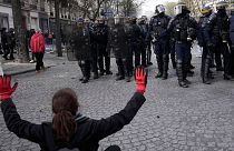 زنی در جریان تظاهرات پنجشنبه ۶ آوریل ۲۰۲۳ در پاریس، دستان خود را در مقابل افسران پلیس ضدشورش بالا می‌برد.