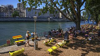People enjoy the sun at Paris Plage event along the Seine River in Paris, Sunday, July 10, 2022. 