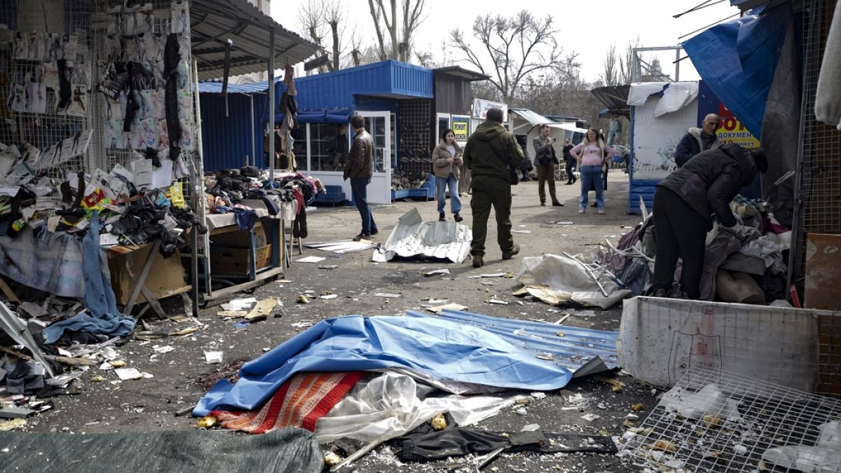 A lifeless body covered by plastic lies on the ground at a street market after the shelling that Russian officials in Donetsk said was conducted by Ukrainian forces.