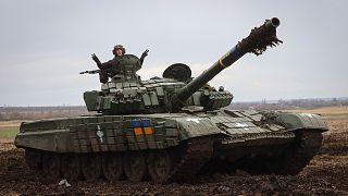 A Ukrainian soldier waves atop a tank as he checks the readiness of equipment for combat deployment, at a military base in Zaporizhzhia region, 5 April 2023