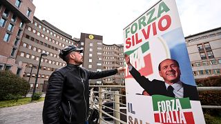 شاب إيطالي يضع لافتة دعم لبرلسكوني أمام مشفى سان رافاييلي