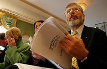 زعيم حزب "شين فين" القومي الأيرلندي جيري أدامز يحمل نسخة من اتفاق السلام