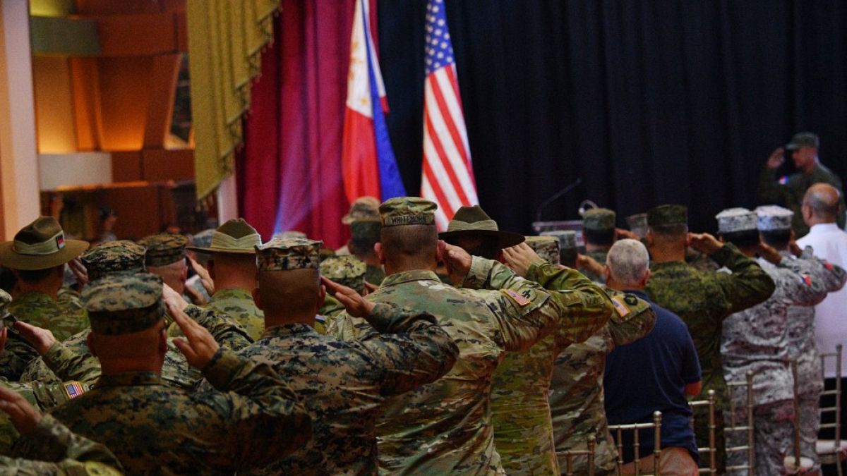 Des soldats américains et philippins saluent leurs drapeaux, à Quezon City, périphérie de Manille, Philippines, le 11 avril 2023