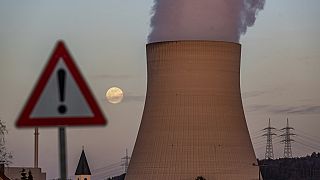 Vapor de agua se eleva desde en la central nuclear Isar 2 detrás de una señal de advertencia, en Essenbach, Alemania