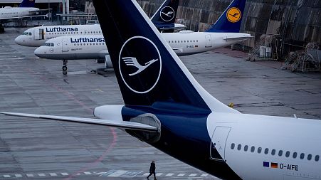 A person walks near parked Lufthansa aircrafts at the airport in Frankfurt, Germany, Sunday, March 26, 2023.