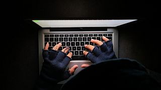 Un hombre utiliza un ordenador en la oscuridad.