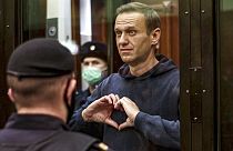 Russian opposition leader Alexei Navalny makes a heart gesture standing in a cage during a hearing in Moscow, Russia.