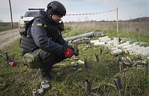 Un démineur du service d'urgence ukrainien ramasse des restes d'obus et de grenade sur un site de déminage, près du village de Kamenka, dans la région de Kharkiv en Ukraine.