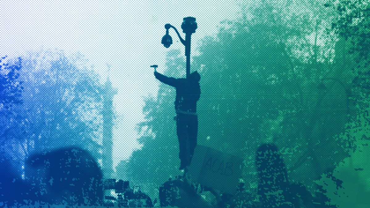 A protester uses a hammer to break a CCTV camera during a demonstration against a security law that would restrict sharing images of police in Paris, November 2020