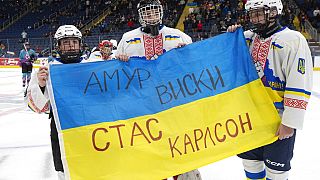 Ivan Bilozerov (balra), Matvii Kulish (középen) és Ihor Malovanyi ukrán jégkorongozók tartják az ukrán zászlót