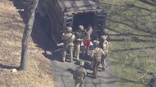 This image made from video provided by WCVB-TV, shows Jack Teixeira, in T-shirt and shorts, being taken into custody by armed tactical agents on Thursday, April 13, 2023, in D