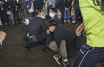 A man, on the ground, who threw what appeared to be a smoke bomb, is caught at a port in Wakayama, western Japan Saturday, April 15, 2023