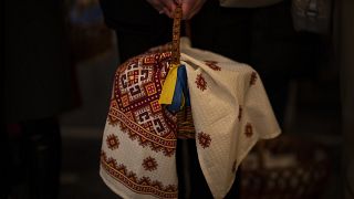 An Orthodox Christian worshiper holds a traditional Easter basket decorated with ribbons in the colors of the Ukrainian national flag during an Easter Sunday service in Kyiv,