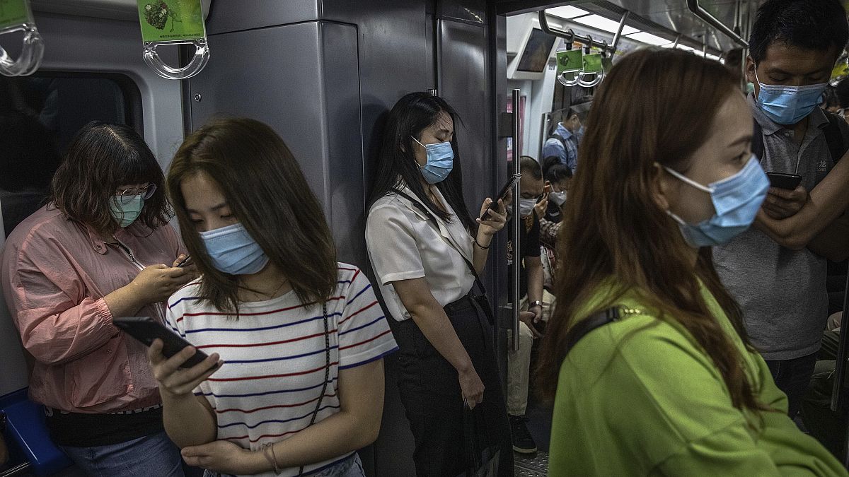 Maszkot viselő emberek a pekingi metrón