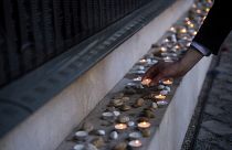 Un hombre enciende una vela en el borde del Muro Conmemorativo de las Víctimas en el Centro Conmemorativo del Holocausto en Budapest, Hungría, el domingo 16 de abril de 2023