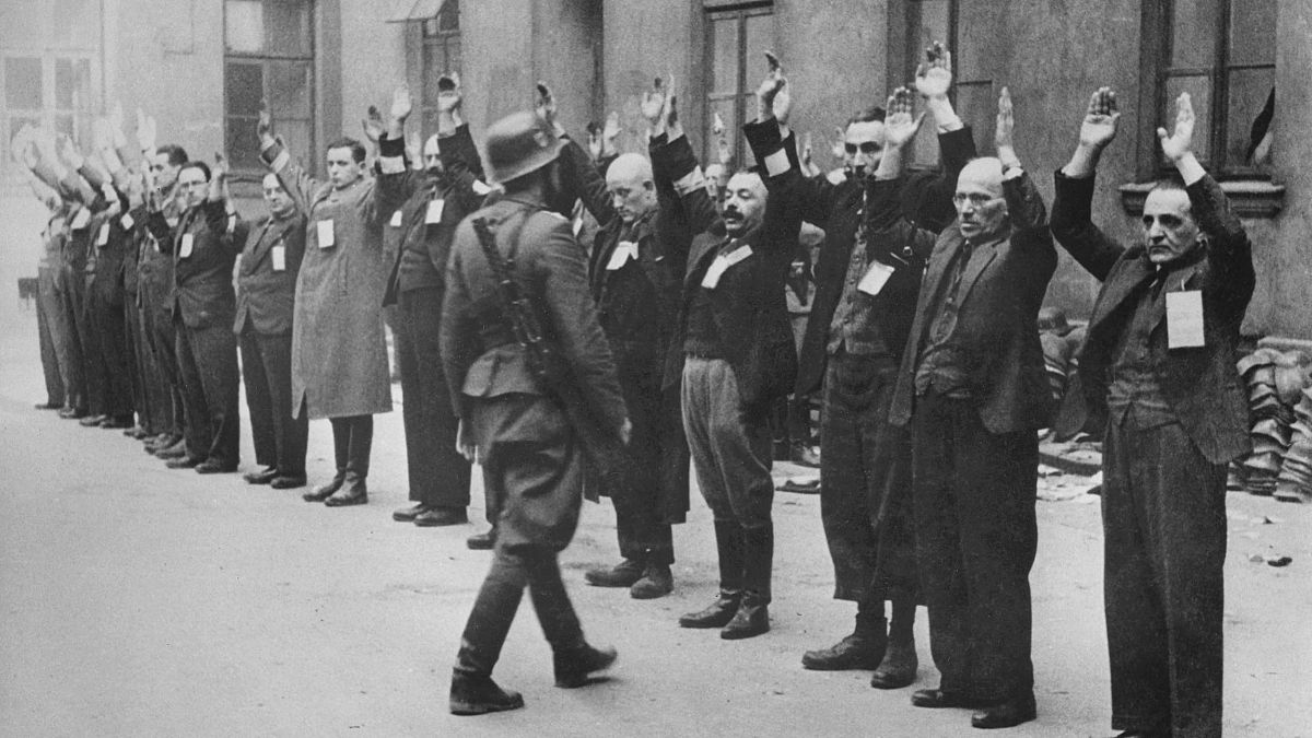 A Nazi SS-man inspects a group of Jewish workers in April 1943 in the Ghetto of Warsaw.