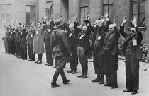 A Nazi SS-man inspects a group of Jewish workers in April 1943 in the Ghetto of Warsaw.