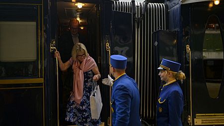 An employee hers a passenger disembark from the Venice Simplon-Orient-Express at Istanbul Station.