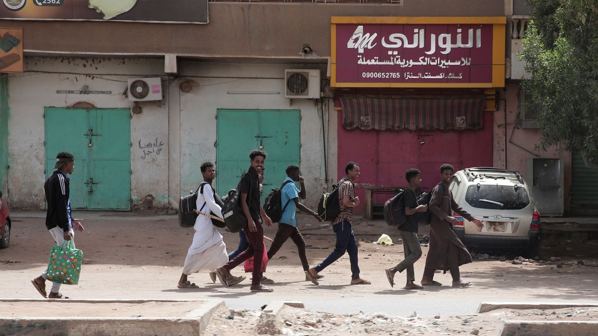 طلاب أمام متاجر مغلقة في الخرطوم في ثالث يوم من الاشتباكات